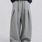 A person wearing wide-leg gray sweatpants with a drawstring waist, paired with a navy hoodie and white sneakers, shown from the chest down against a light gray studio background.